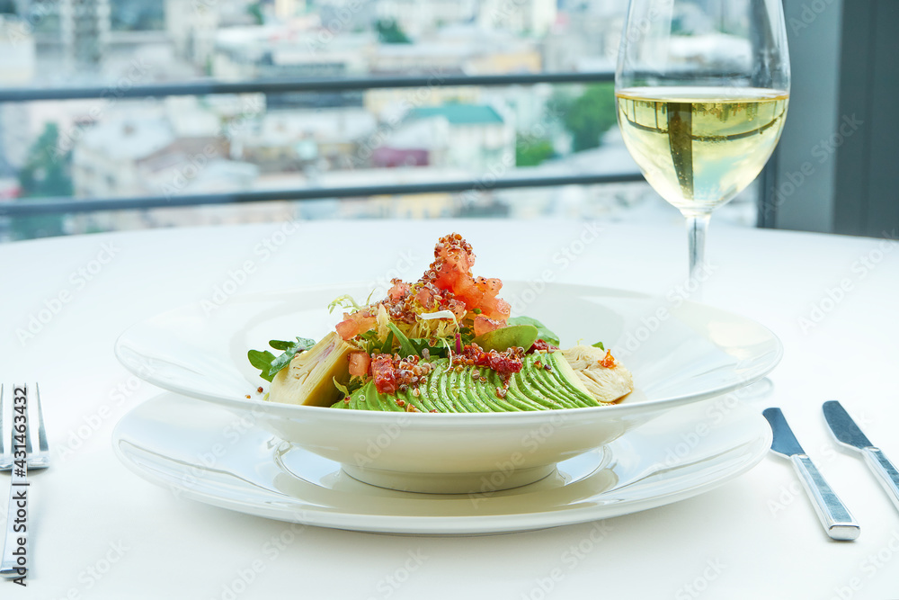 A delicious and healthy salad with artichokes, avocado, tuna and quinoa, served in a white plate on a white tablecloth. Restaurant food service A delicious and healthy salad with artichokes, avocado, tuna and quinoa, served in a white plate on a white tablecloth. Restaurant food service