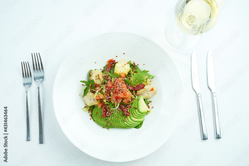 A delicious and healthy salad with artichokes, avocado, tuna and quinoa, served in a white plate on a white tablecloth. Restaurant food service A delicious and healthy salad with artichokes, avocado, tuna and quinoa, served in a white plate on a white tablecloth. Restaurant food service