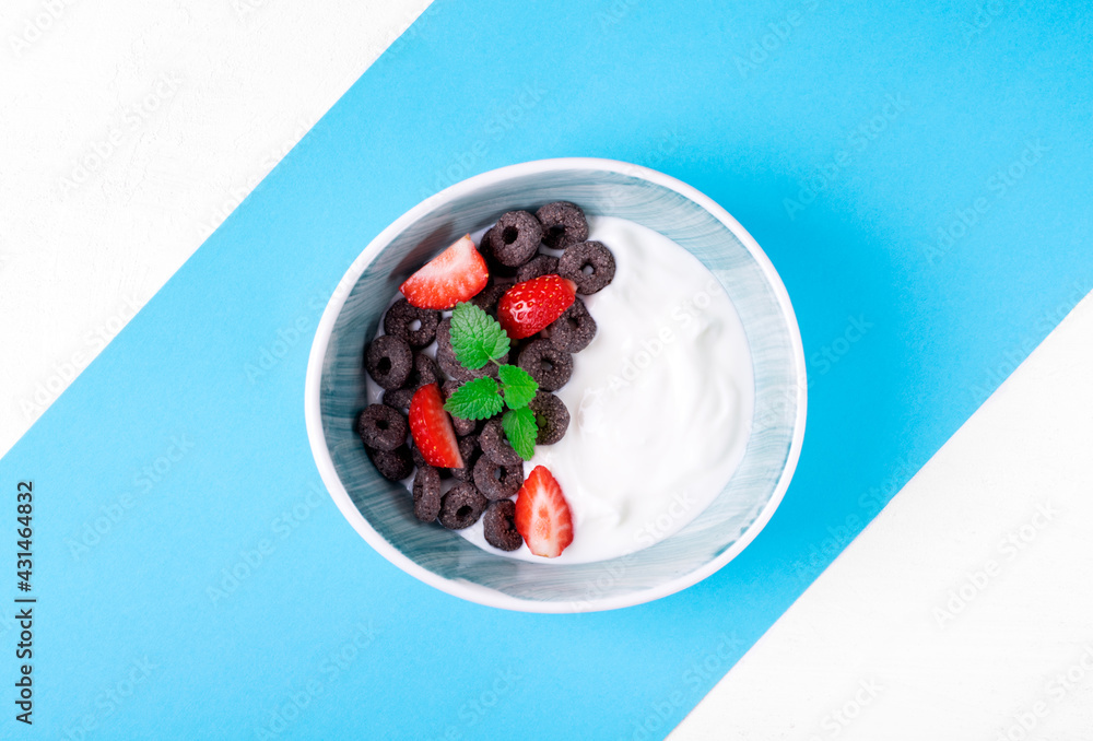Yogurt with black cereals and strawberry in the bowl on geometric blue and white background. Top view. Breakfast meal Yogurt with black cereals and strawberry in the bowl on geometric blue and white background. Top view. Breakfast meal