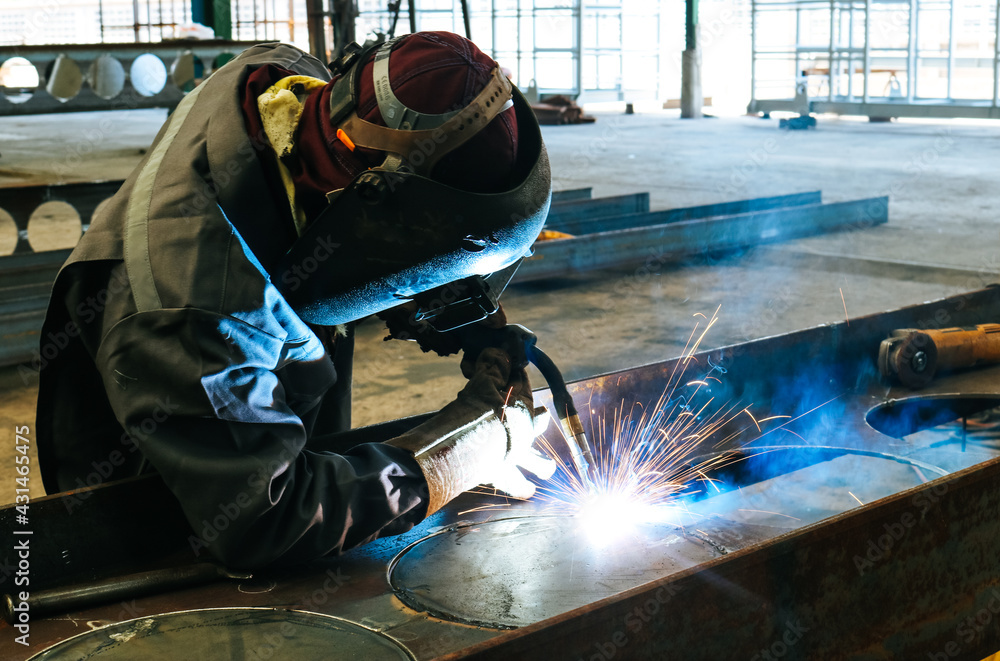 Craftsman welding steel structure h-beam with sparks fly from gas machine in fabrication factory. Craftsman welding steel structure h-beam with sparks fly from gas machine in fabrication factory.