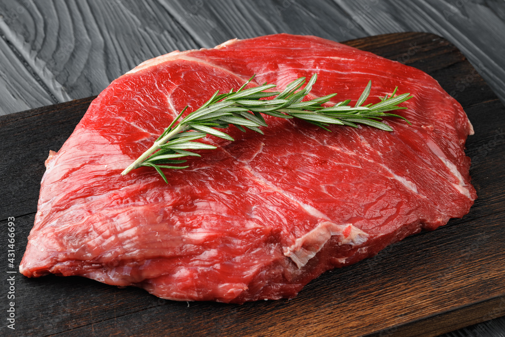 Raw beef fillet piece on wooden board close up