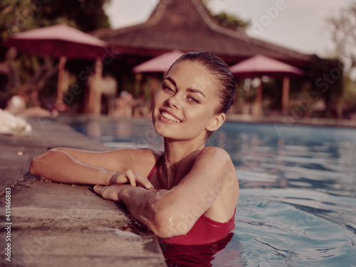 cheerful woman in a swimsuit tanning summer pool luxury tropics