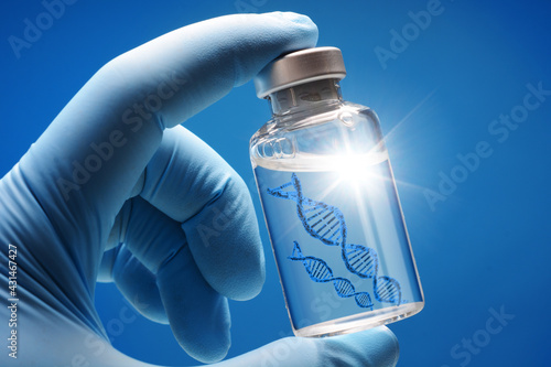 Doctor or scientist shows a vial of genetic agent as a vaccine or therapy against Corona or Covid-19 as a symbolic image photo