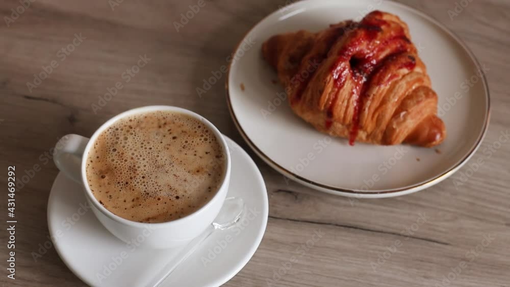 Pouring hot water in cup with black coffee. Delicious fresh french croissant with strawberry filling and cup of aromatic coffee on wooden table Pouring hot water in cup with black coffee. Delicious fresh french croissant with strawberry filling and cup of aromatic coffee on wooden table