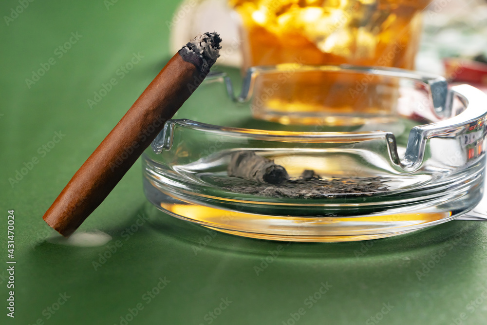 Close up of smoking cigar and whiskey glass on table - obrazy, fototapety, plakaty 