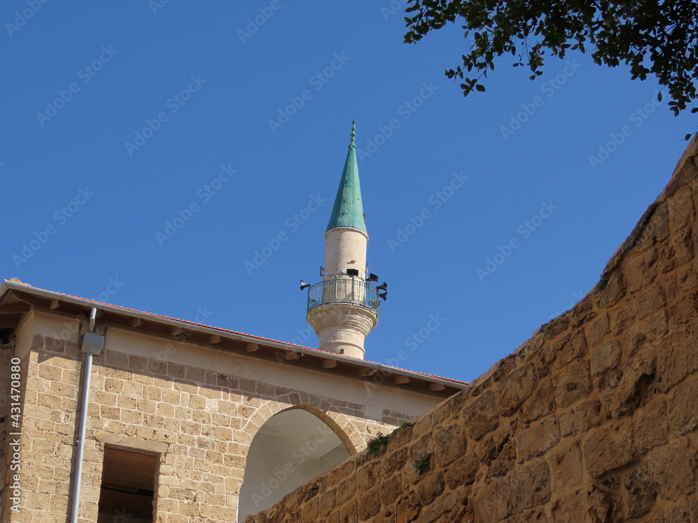 Street in the old city of Acre in Israel. Nice view of the minaret against the blue sky.