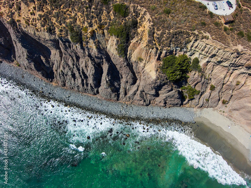 a stunning aerial shot of the coastline with vast blue and green ocean water, lush green hillsides with homes and waves crashing into the beach at Baby Beach in Dana Point California photo