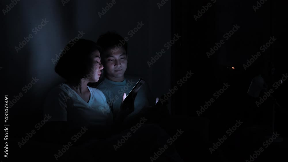 Asian couple with mobile devices at home. Connection, Communication, Entertainment, Fun from smartphone, night shots Asian couple with mobile devices at home. Connection, Communication, Entertainment, Fun from smartphone, night shots