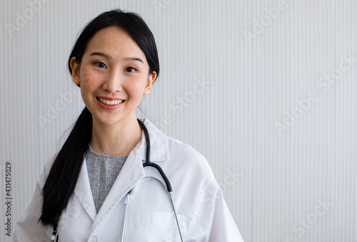 Asian woman doctor long black hair smiling look at camera wearing white uniform with stethoscope on her neck. Looks happy friendly and professional.