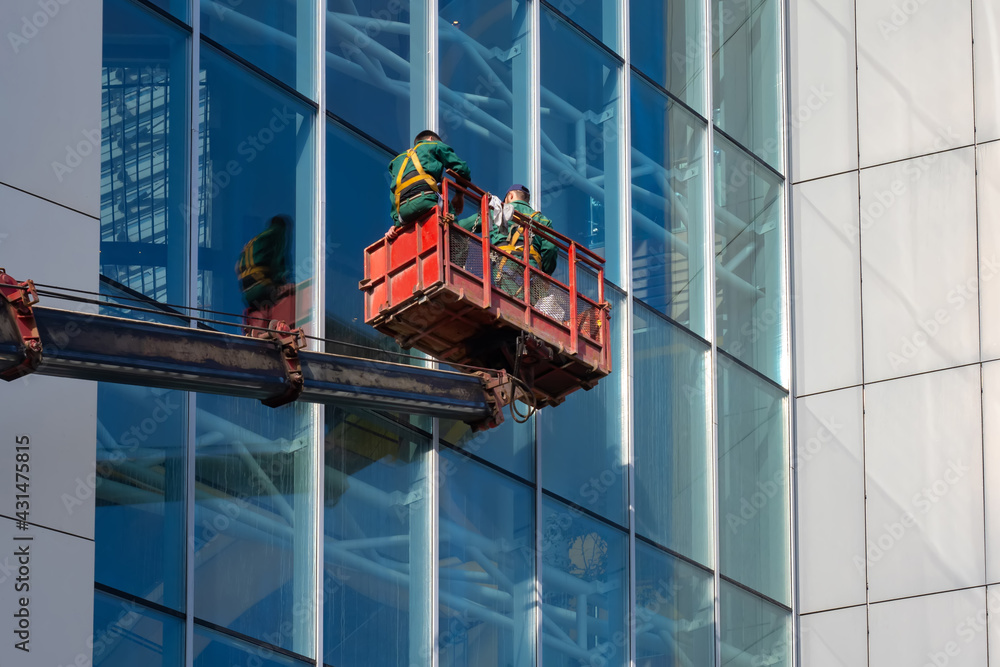 Washing the windows of a skyscraper. Workers in the cradle wash the