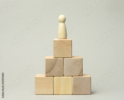 wooden figurine of a man at the top of the pyramid. The concept of career growth, goal achievement