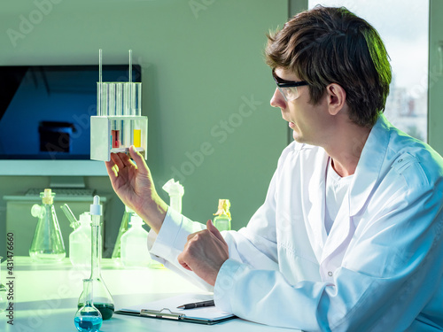 Chemist sits and examines c...
