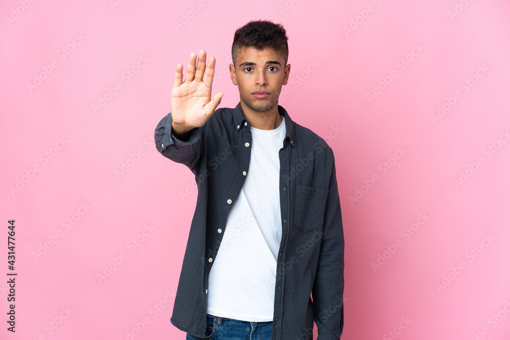 Young Brazilian man isolated on pink background making stop gesture Young Brazilian man isolated on pink background making stop gesture