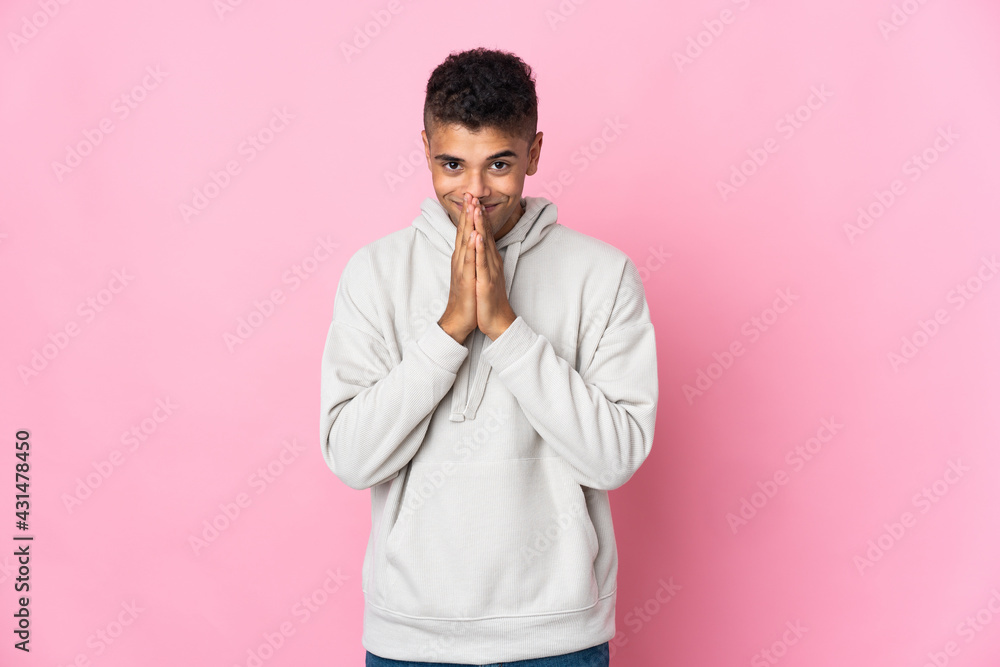 Young Brazilian man isolated on pink background keeps palm together. Person asks for something Young Brazilian man isolated on pink background keeps palm together. Person asks for something