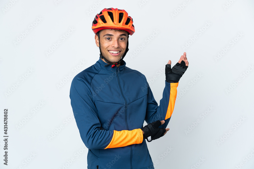 Young cyclist Brazilian man isolated on white background extending hands to the side for inviting to come - obrazy, fototapety, plakaty 