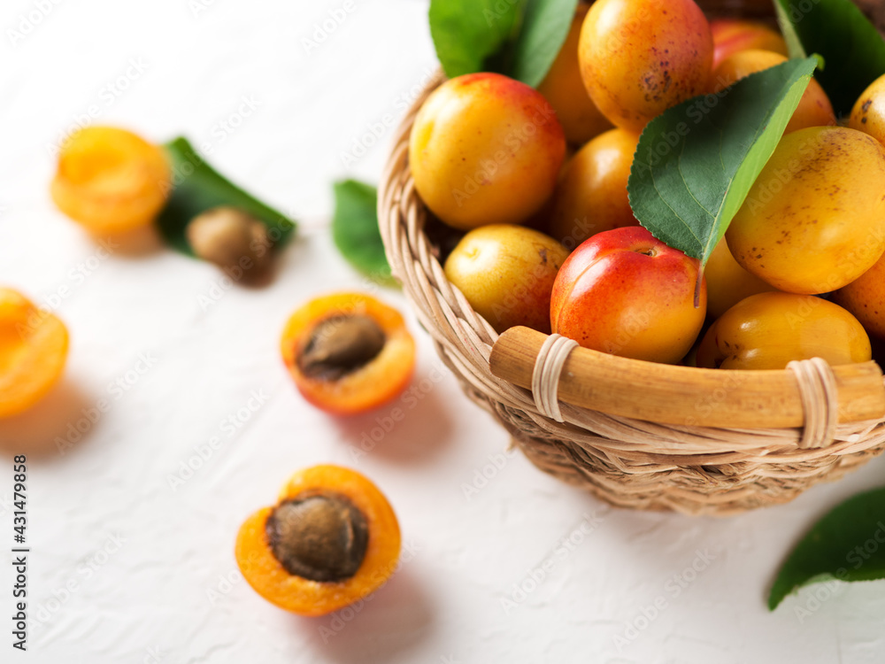 Ripe apricots in a wicker wooden basket on a white stone table Ripe apricots in a wicker wooden basket on a white stone table