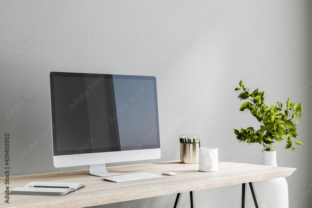 Modern computer monitor on wooden table with white keyboard, notebook and coffee mug on light grey wall background in stylish room Modern computer monitor on wooden table with white keyboard, notebook and coffee mug on light grey wall background in stylish room