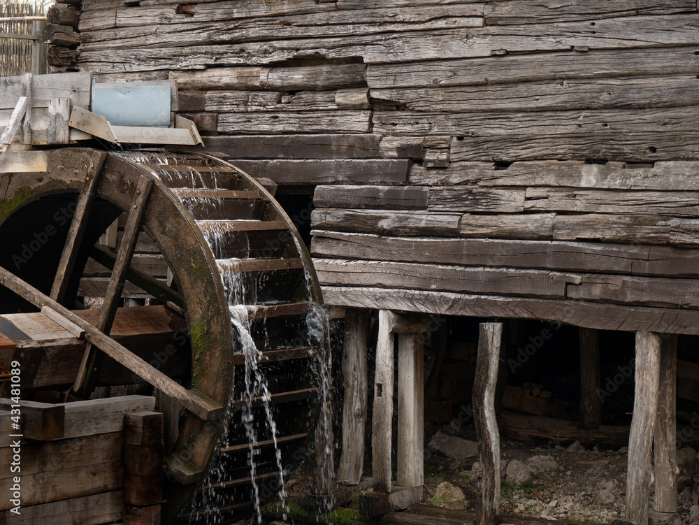 Water mill wheel rotates under a stream of water. Traditional village machinery Water mill wheel rotates under a stream of water. Traditional village machinery