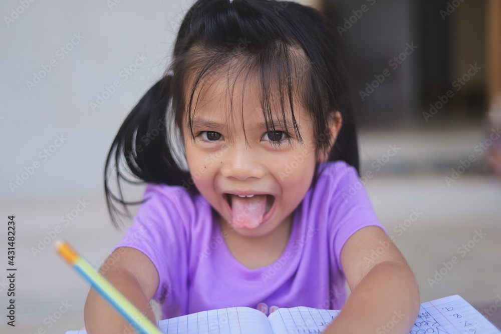 A cute Asian girl doing homework in her home during the day. A cute Asian girl doing homework in her home during the day.
