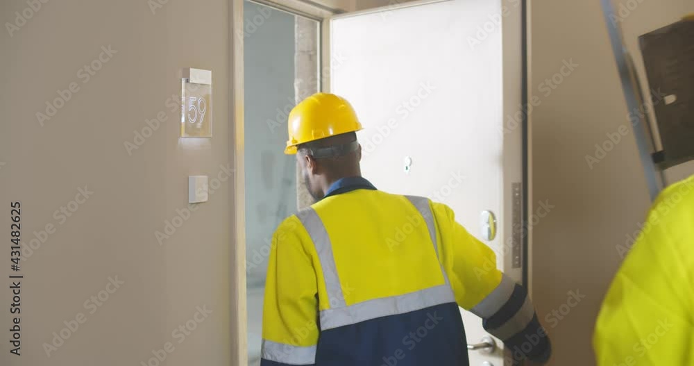 Close up of professional builders in uniform walking in renovating apartment Close up of professional builders in uniform walking in renovating apartment