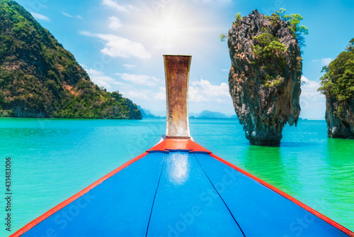 Amazing thai traditional wooden longtail boat view with James Bond island near Koh Panyee village, Phangnga province. One landmark of the most famous tourist attraction in southern Thailand. © sakarin14