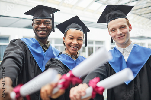 Valokuva Diverse group of college graduates holding diploma certificates and smiling at c