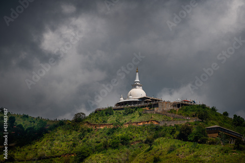 Mahamevnawa Buddhist Monastery temple in the mountain top low angle scenic landscape view. dark rainy clouds and cold atmosphere in Bandarawela, stupa glowing brightly in the distant hill.