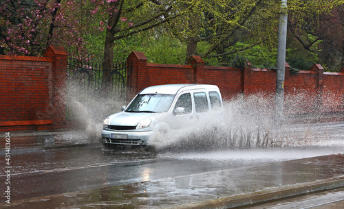 Samochód wpada w kałużę wody na jezdni powodująć rozbryzg. 