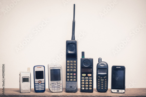 Group of old and obsolete mobile phone or cell phone on old wood with a light rough background