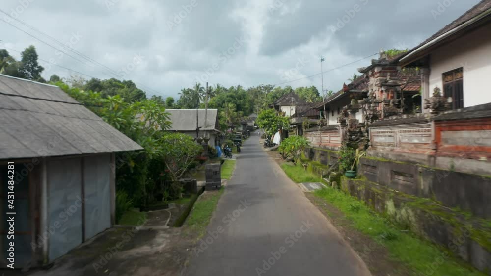 Low flying aerial pov shot down the traditional street in the residential community in Bali, Indonesia Low flying aerial pov shot down the traditional street in the residential community in Bali, Indonesia