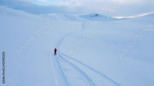 Cross country skier traveling across a snowy arctic tundra in the high mountains on a cold winters day.