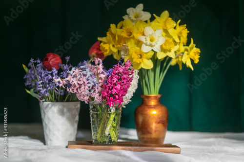 Bouquets of spring flowers yellow white narcissus, tulips, hyacinth arranged in vases placed on the table.