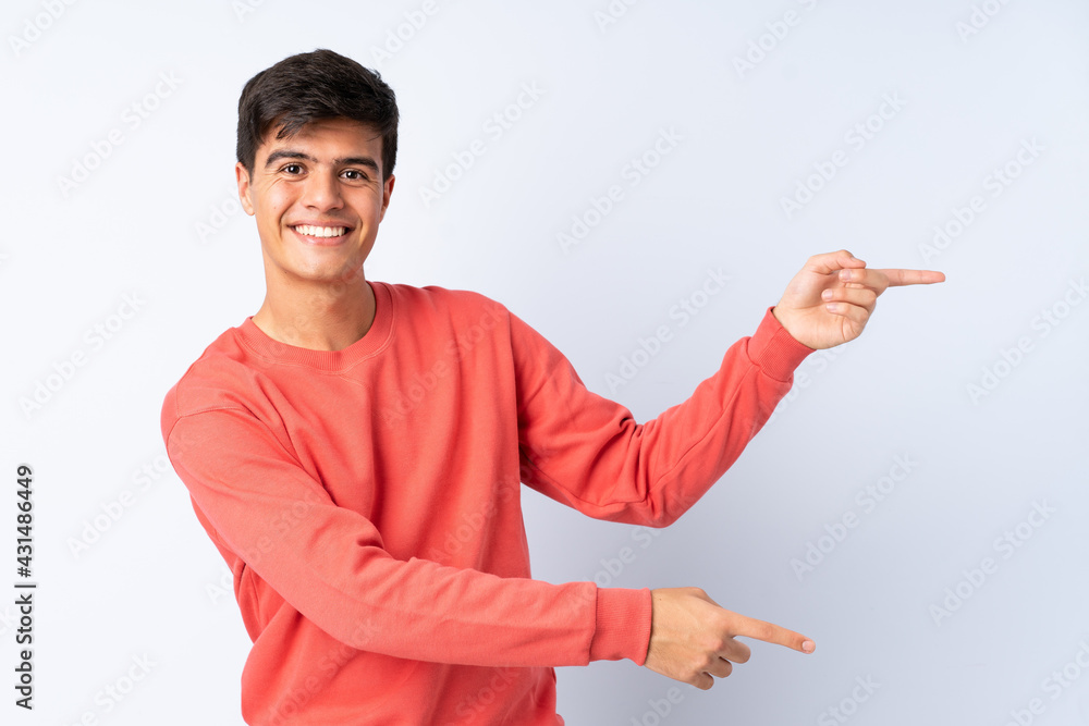 Handsome man over isolated blue background pointing finger to the side and presenting a product Handsome man over isolated blue background pointing finger to the side and presenting a product