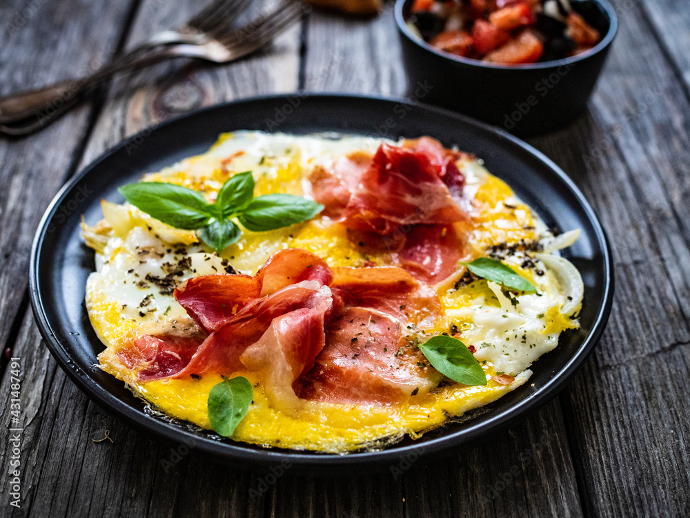Breakfast - scrambled eggs with serrano ham and vegetable salad on wooden table
Breakfast - scrambled eggs with serrano ham and vegetable salad on wooden table