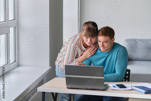 Young Man showing how to use computer to an old woman. elders technology concept. Middle aged man helping his mother use a laptop computer at home, close up