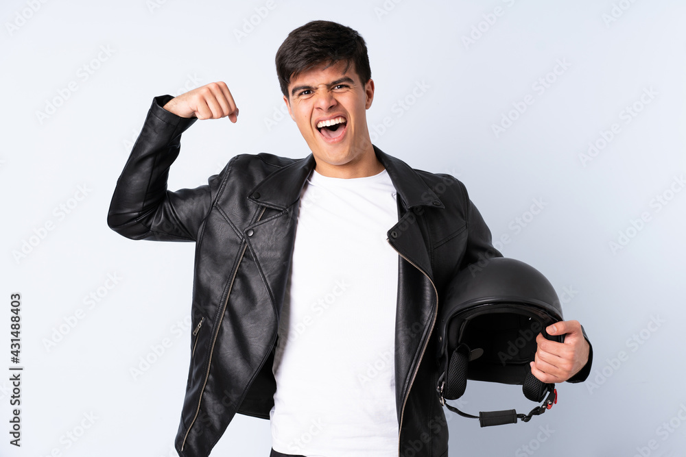Man with a motorcycle helmet over isolated blue background celebrating a victory Man with a motorcycle helmet over isolated blue background celebrating a victory