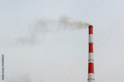 Large smoking chimney. Color is red and white. Climbing ladder and circular platforms. Background is the sky. Production concept, heating plant, environmental pollution by emissions.