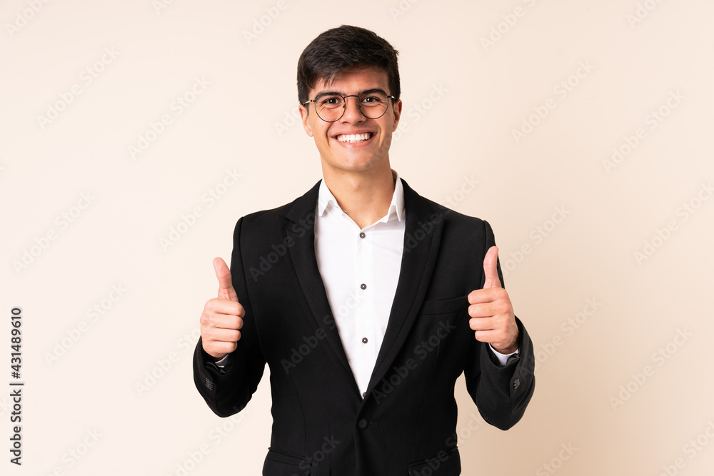 Businessman over isolated beige background giving a thumbs up gesture Businessman over isolated beige background giving a thumbs up gesture