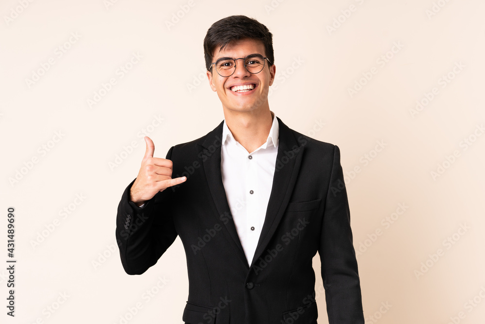 Businessman over isolated beige background making phone gesture