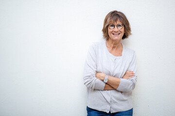 smiling older woman with arms crossed by white background