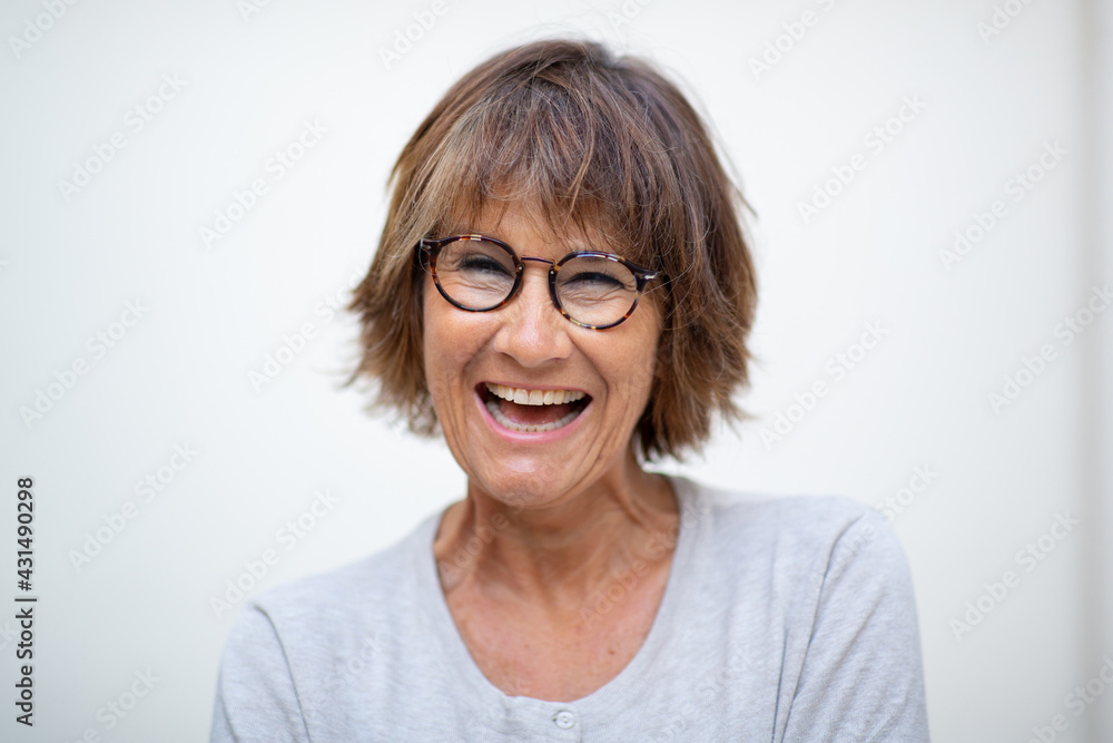 Close up older woman laughing with eyeglasses by white background