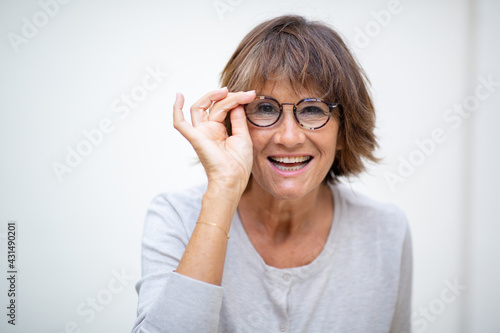 older woman smiling with eyeglasses by white background