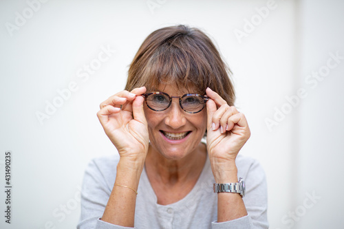 Close up older woman smiling with eyeglasses by white background