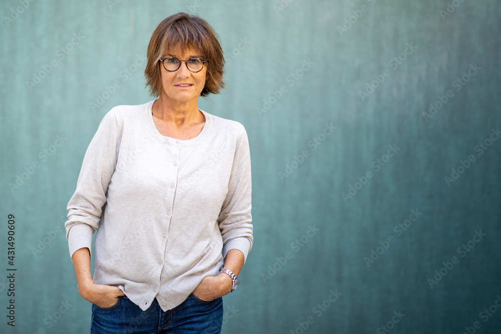 older woman with serious expression and eyeglasses by green background older woman with serious expression and eyeglasses by green background