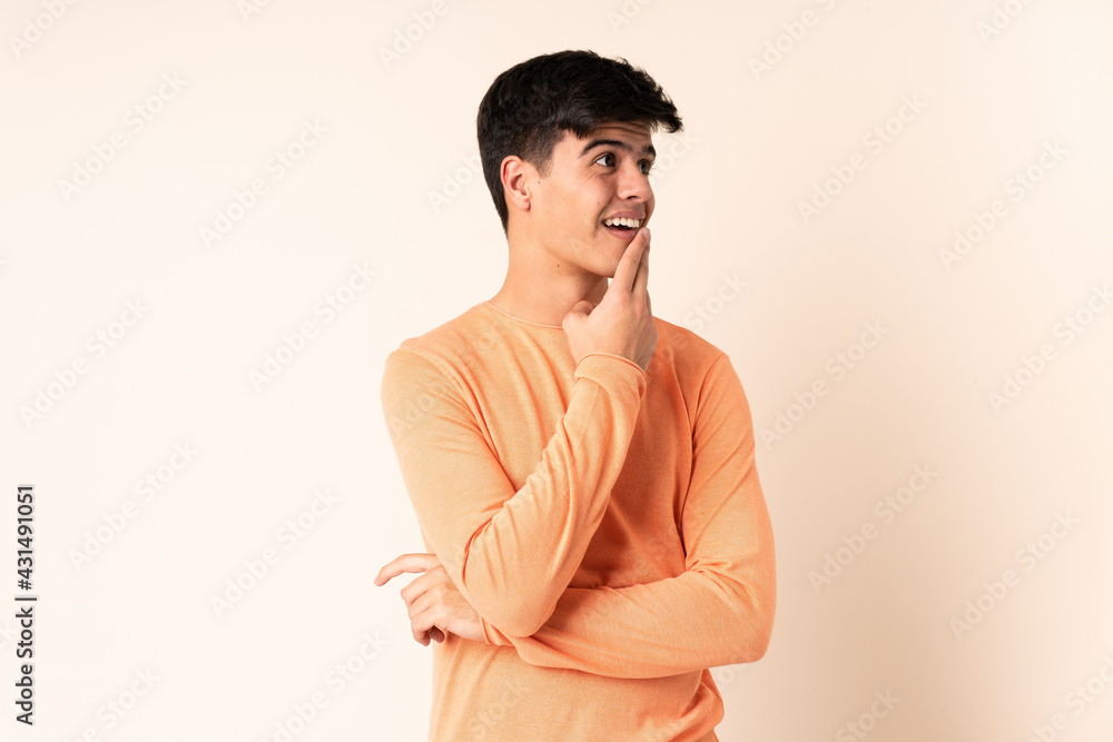Handsome man over isolated beige background looking up while smiling Handsome man over isolated beige background looking up while smiling