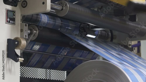 Flexo printing. Printing house. Shaft rotates rapidly. Film spins on shafts. Rroller machine prints. Anilox shafts photo