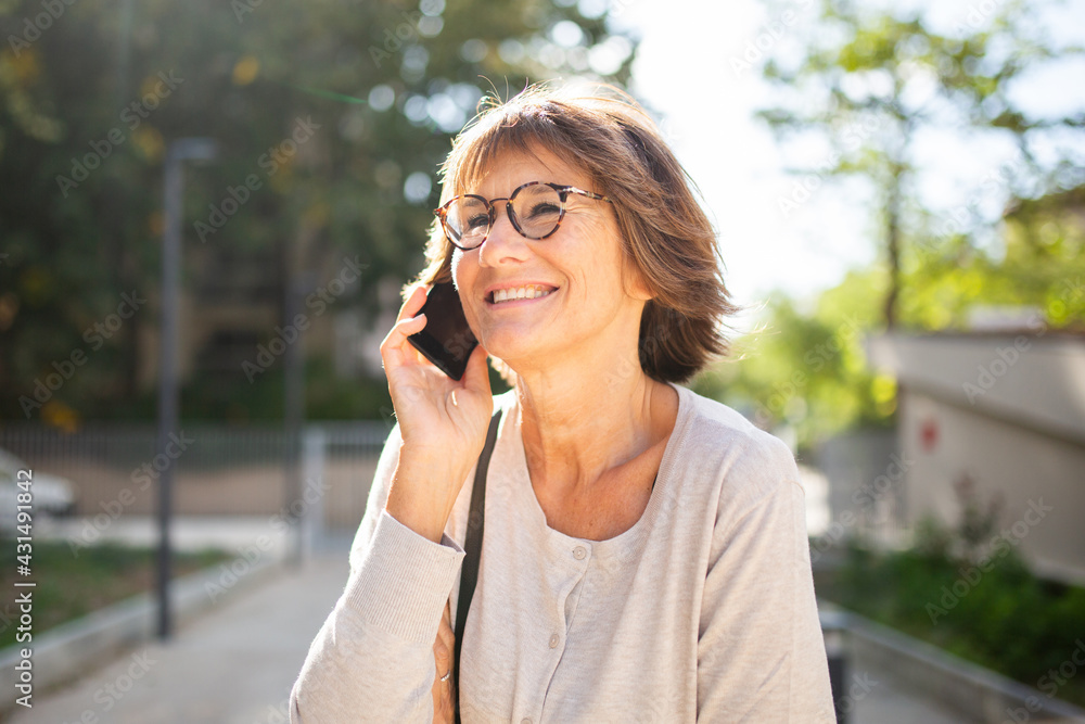 Close up smiling older woman talking with mobile phone outside Close up smiling older woman talking with mobile phone outside