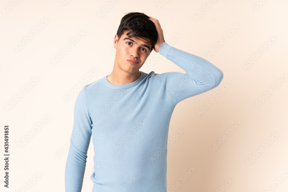 Handsome man over isolated beige background with an expression of frustration and not understanding Handsome man over isolated beige background with an expression of frustration and not understanding