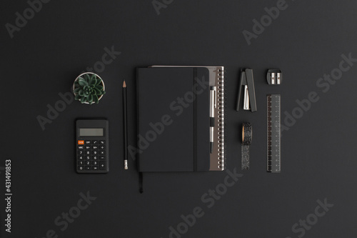 Obraz na płótnie Black leather office table with calculator, notebook and green plant