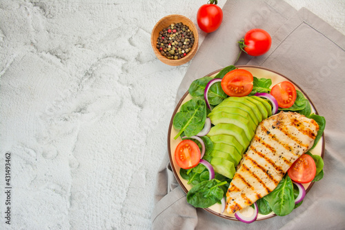 Grilled chicken breast and fresh vegetable salad with spinach leaves, avocado and tomatoes on a light background. Salad of greens with meat. The concept of diet food. Copy space. Food banner.
